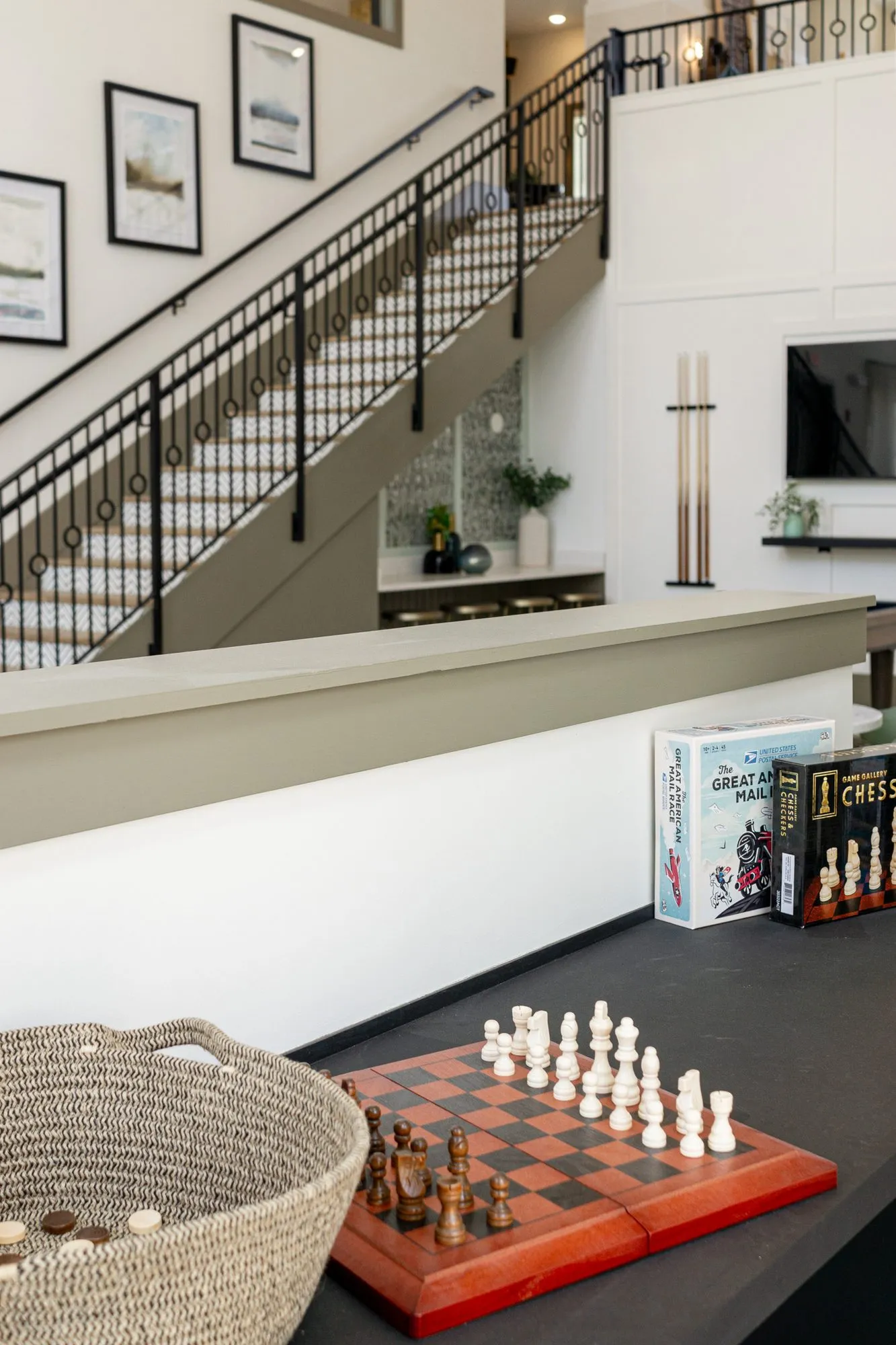 Multifamily interior detail: chess set and board game boxes on a dark counter, the iron stair beyond