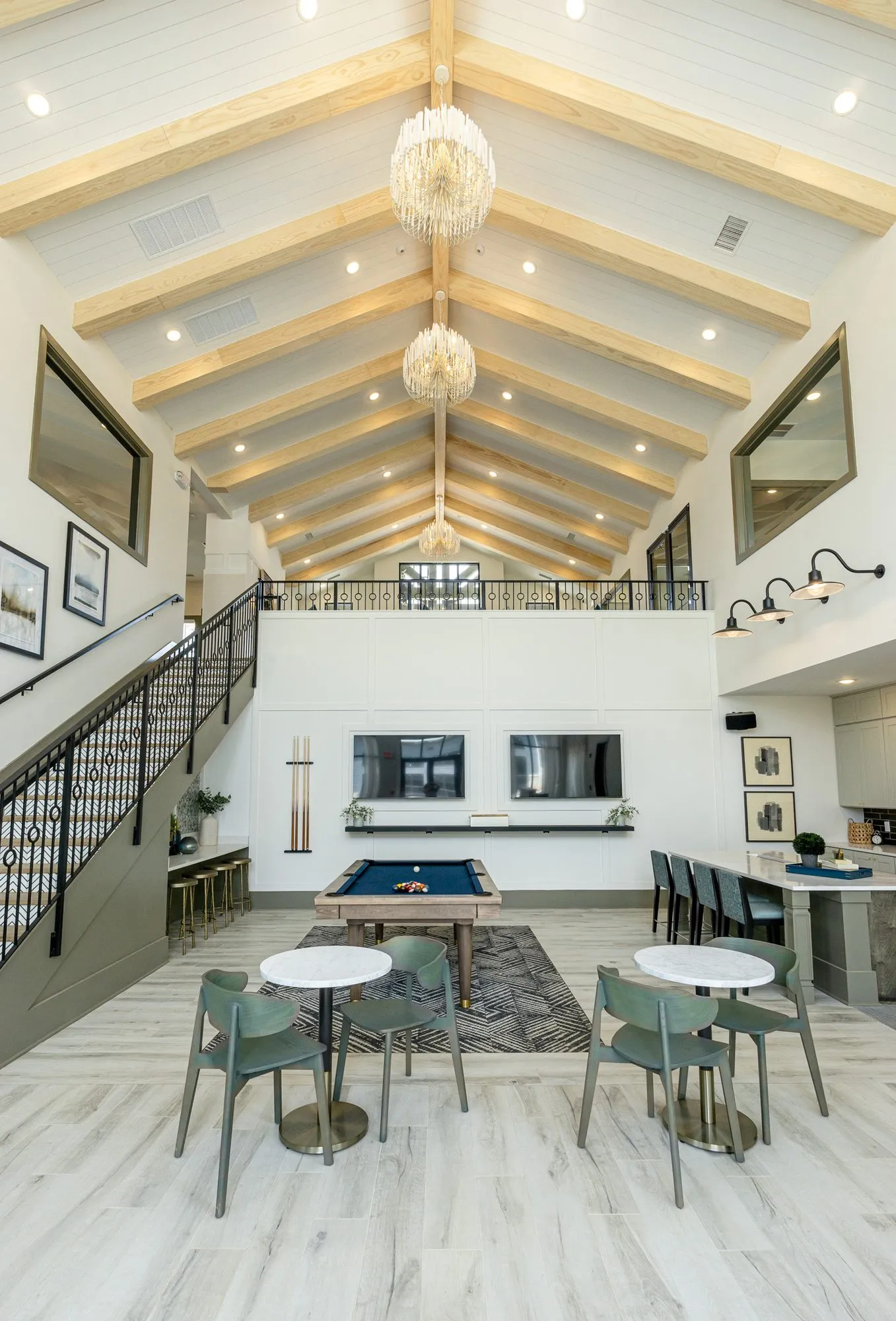 Multifamily amenity clubroom at full height, glass globe chandeliers on the timber vault above the billiards table