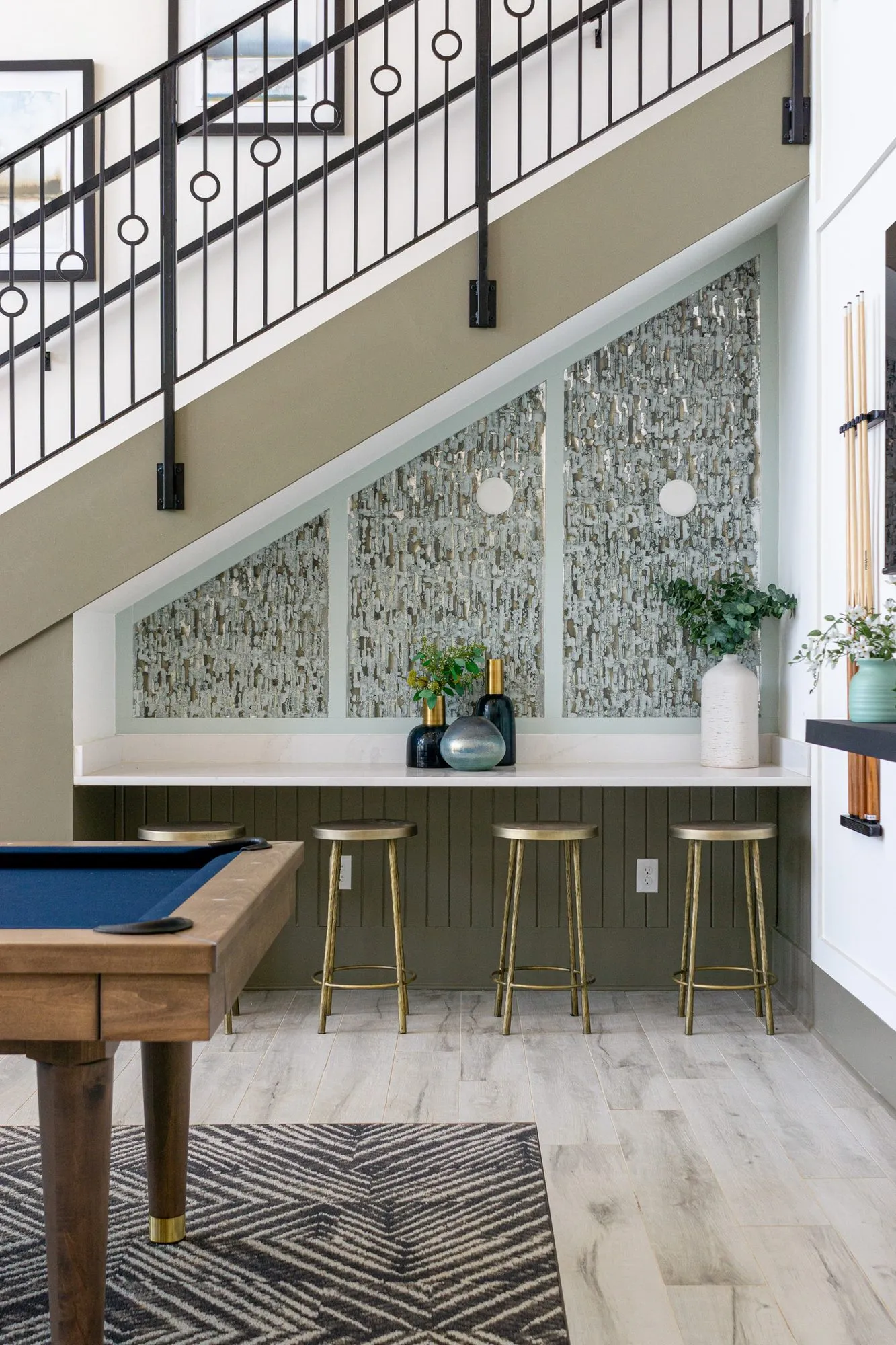 Multifamily interior detail: stair alcove counter with four brass stools under panels of textured metallic tile