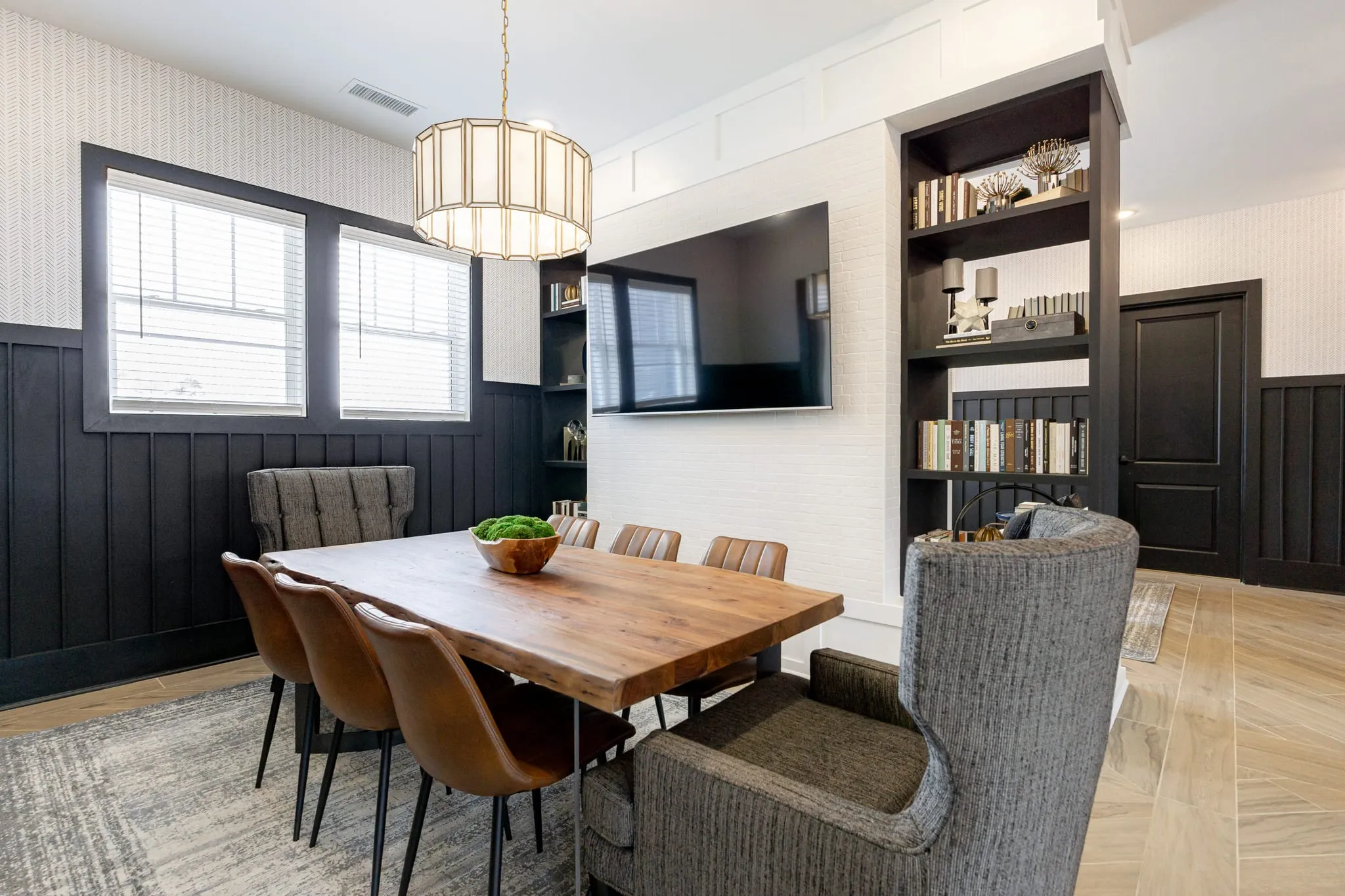 Multifamily amenity business center with a wood table and leather chairs against dark shiplap with built-in shelving