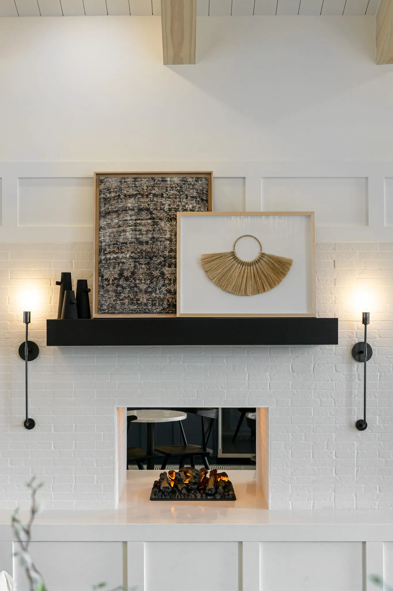 Multifamily interior detail: fireplace with a white brick surround, a black mantel and slim sconces on either side