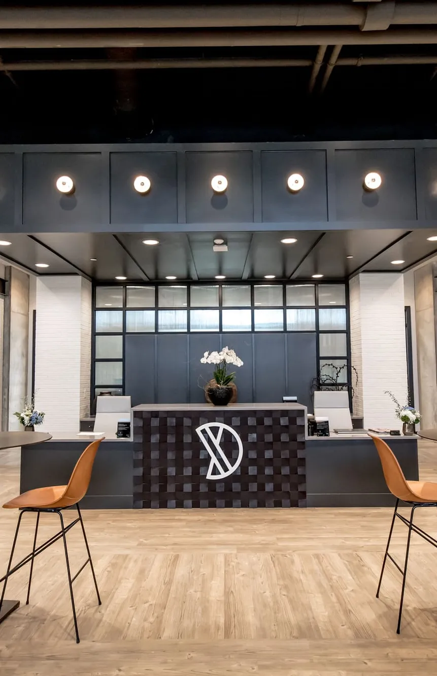 Multifamily leasing lobby under a box of bare bulbs with white brick walls, interior design by Banko Design at Deca at Camperdown, Greenville, South Carolina