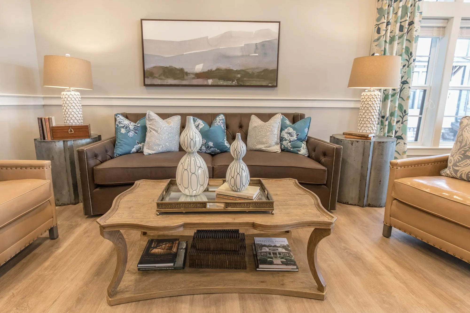 Senior living seating group with a brown tufted sofa, tan leather armchairs and a carved wood coffee table by the window