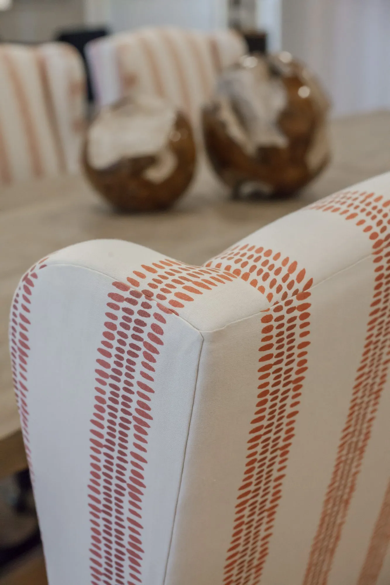 Senior living interior detail: orange and white striped chair back, wood sculptures on the dining table behind