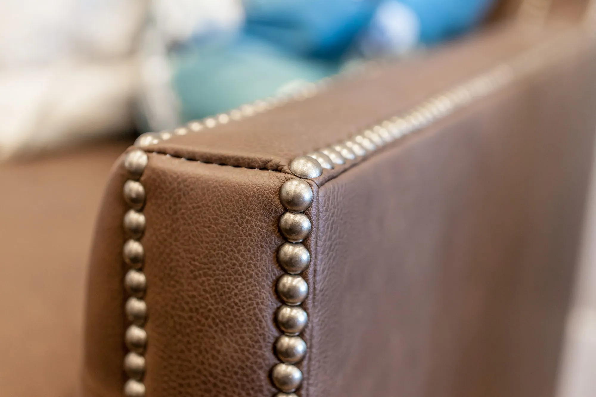 Senior living interior detail: nailhead trim on a brown leather armchair