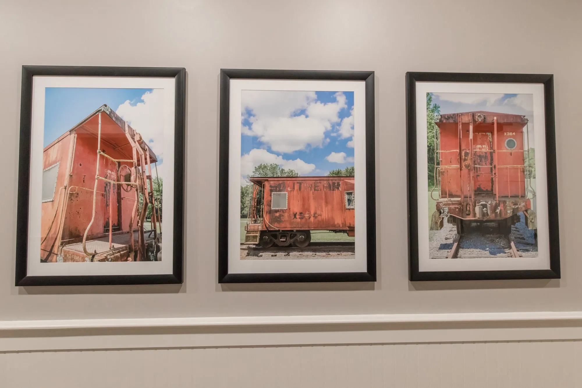 Senior living interior detail: three framed photographs of a weathered red caboose on a grey wall