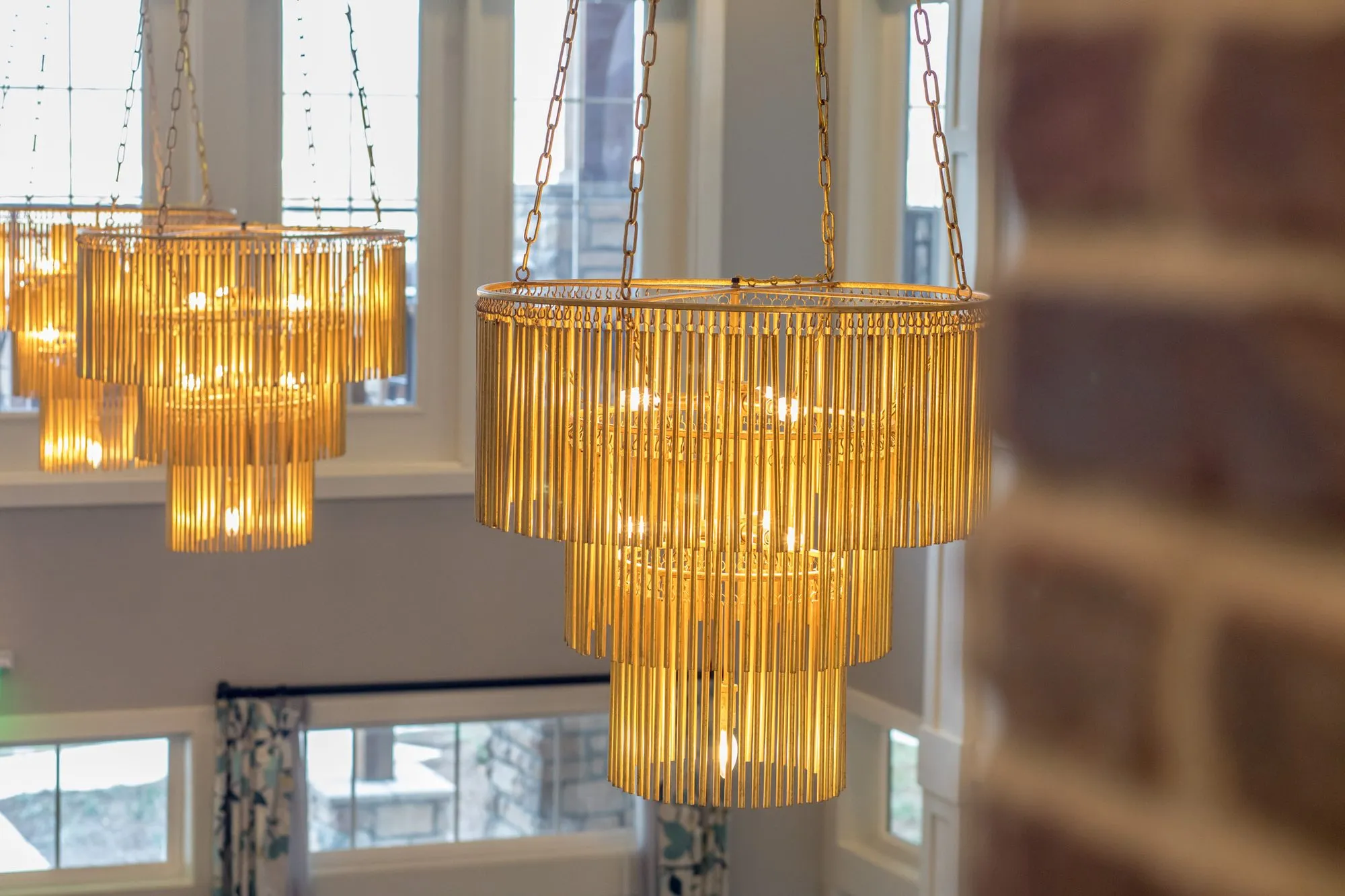 Senior living great room detail: tiered amber glass rod chandeliers hanging in the two-storey space