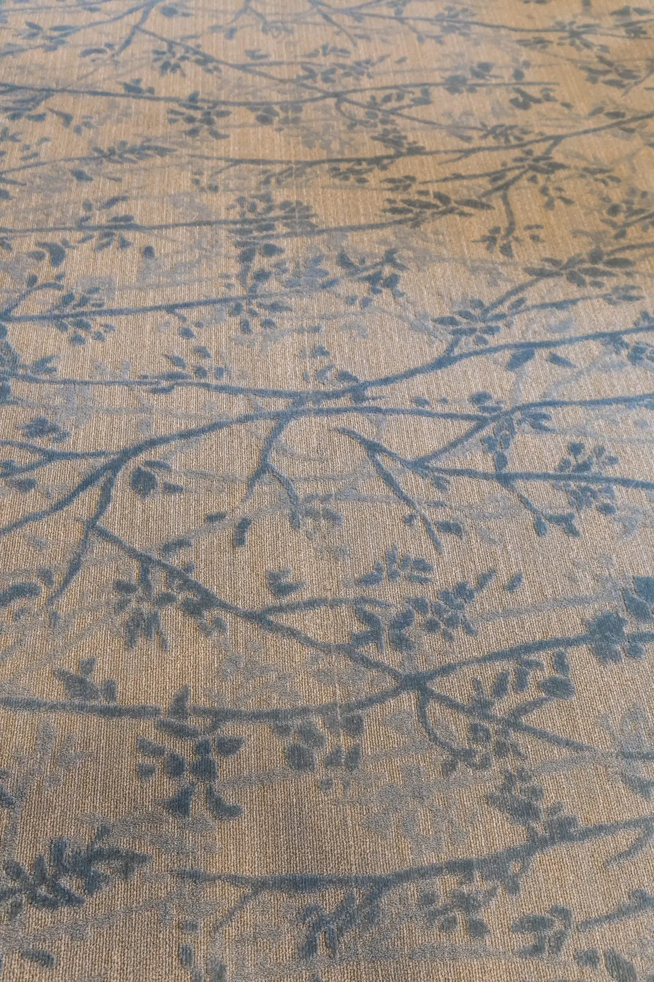 Senior living interior detail: carpet with a blue branch and blossom pattern on a tan ground
