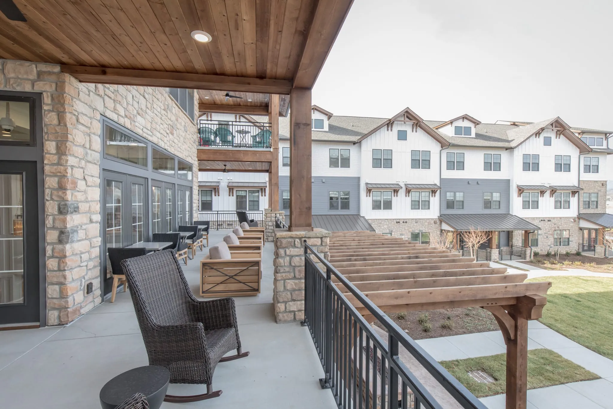 Senior living covered porch with woven rocking chairs looking out over the pergola and the residences