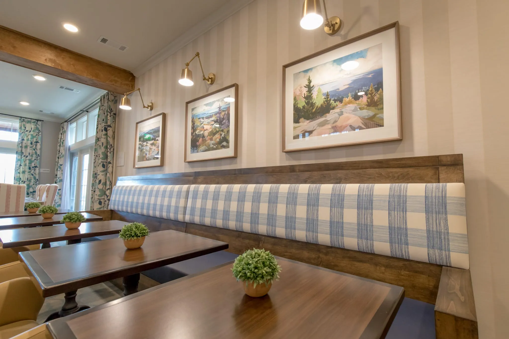 Senior living dining nook with a long blue plaid banquette beneath framed mountain landscape prints