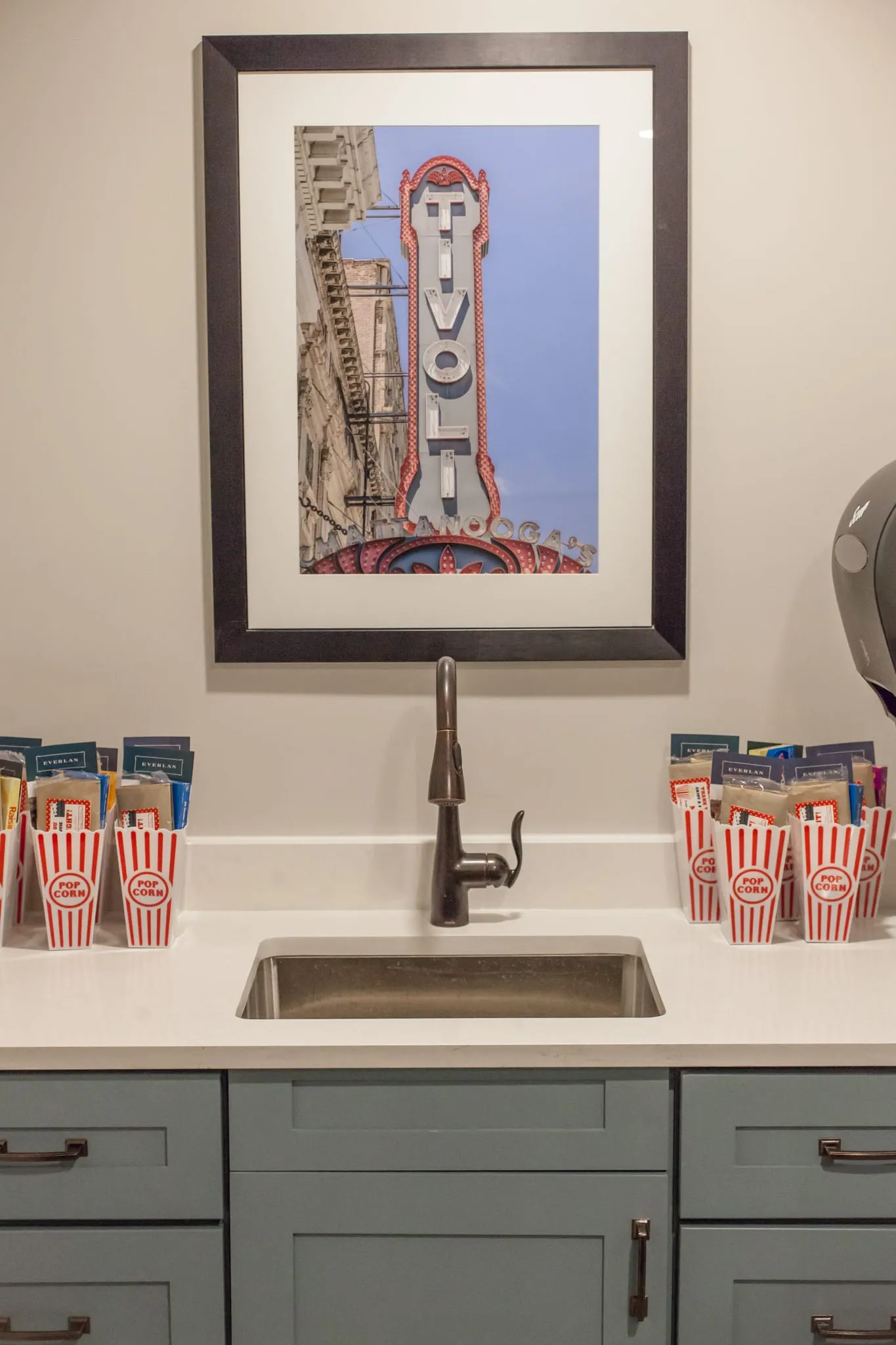 Senior living theater concession counter with popcorn boxes and a framed marquee print above the sink