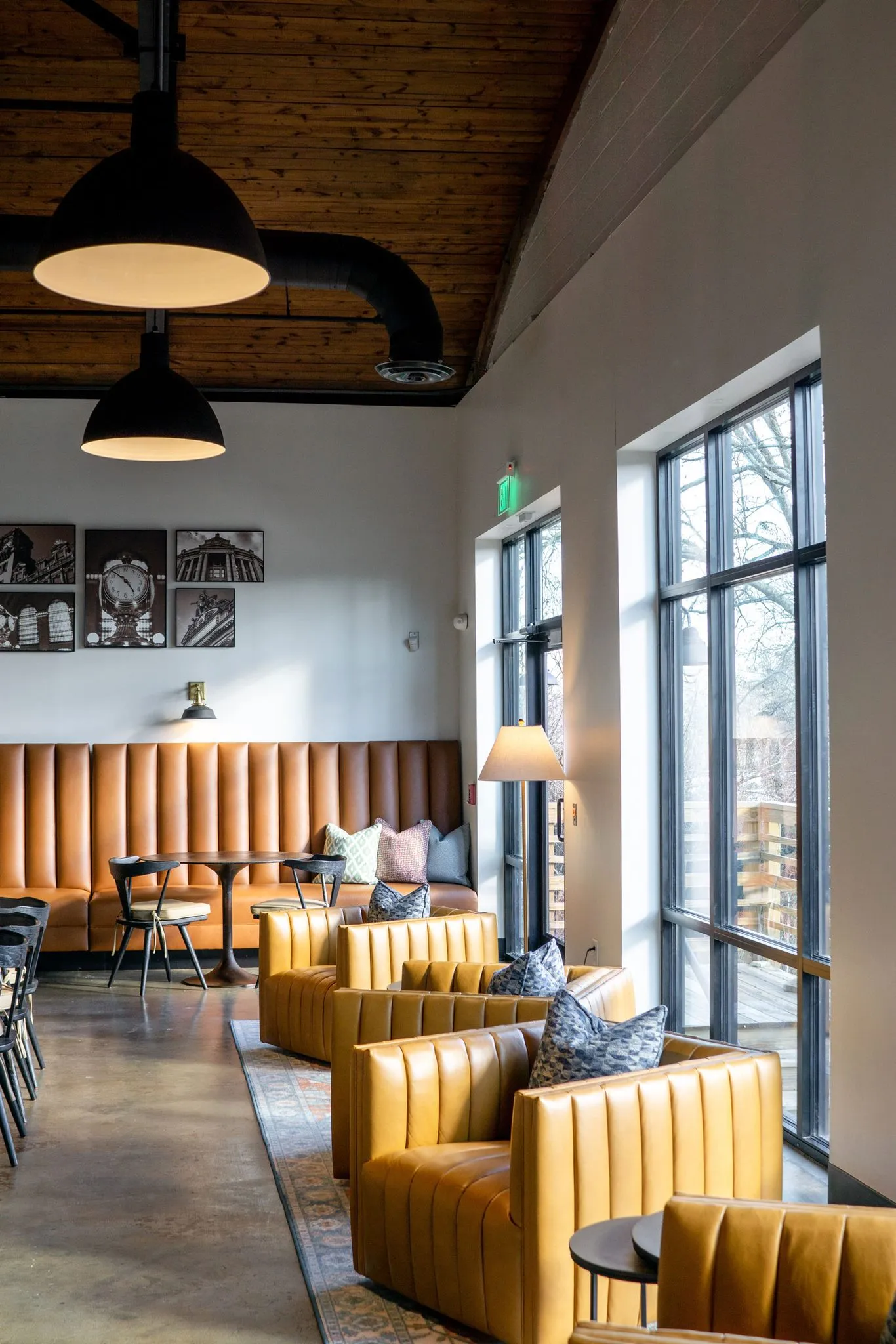 Office banquette corner with camel seating and armchairs pulled up to the tall windows