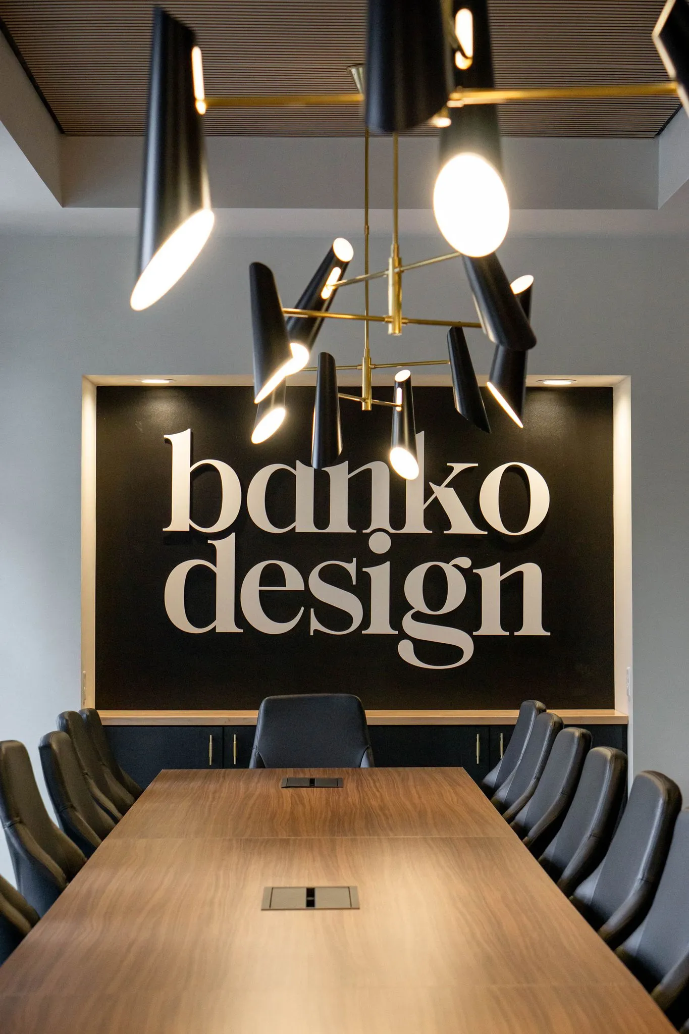 Office conference room with a backlit wordmark behind a walnut table and leather chairs, interior design by Banko Design at Glover Street, Marietta, Georgia