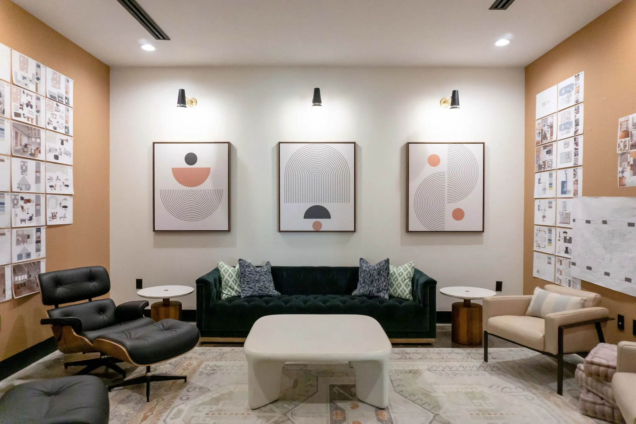 Office studio lounge with a dark green tufted sofa and black leather lounge chair around a white sculptural table