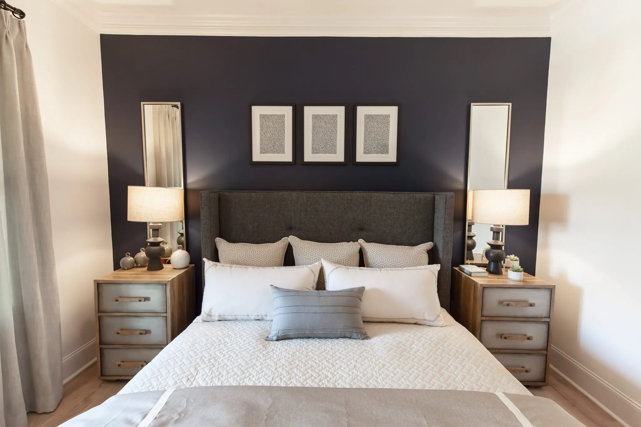 Multifamily apartment bedroom with a navy accent wall behind an upholstered wingback headboard