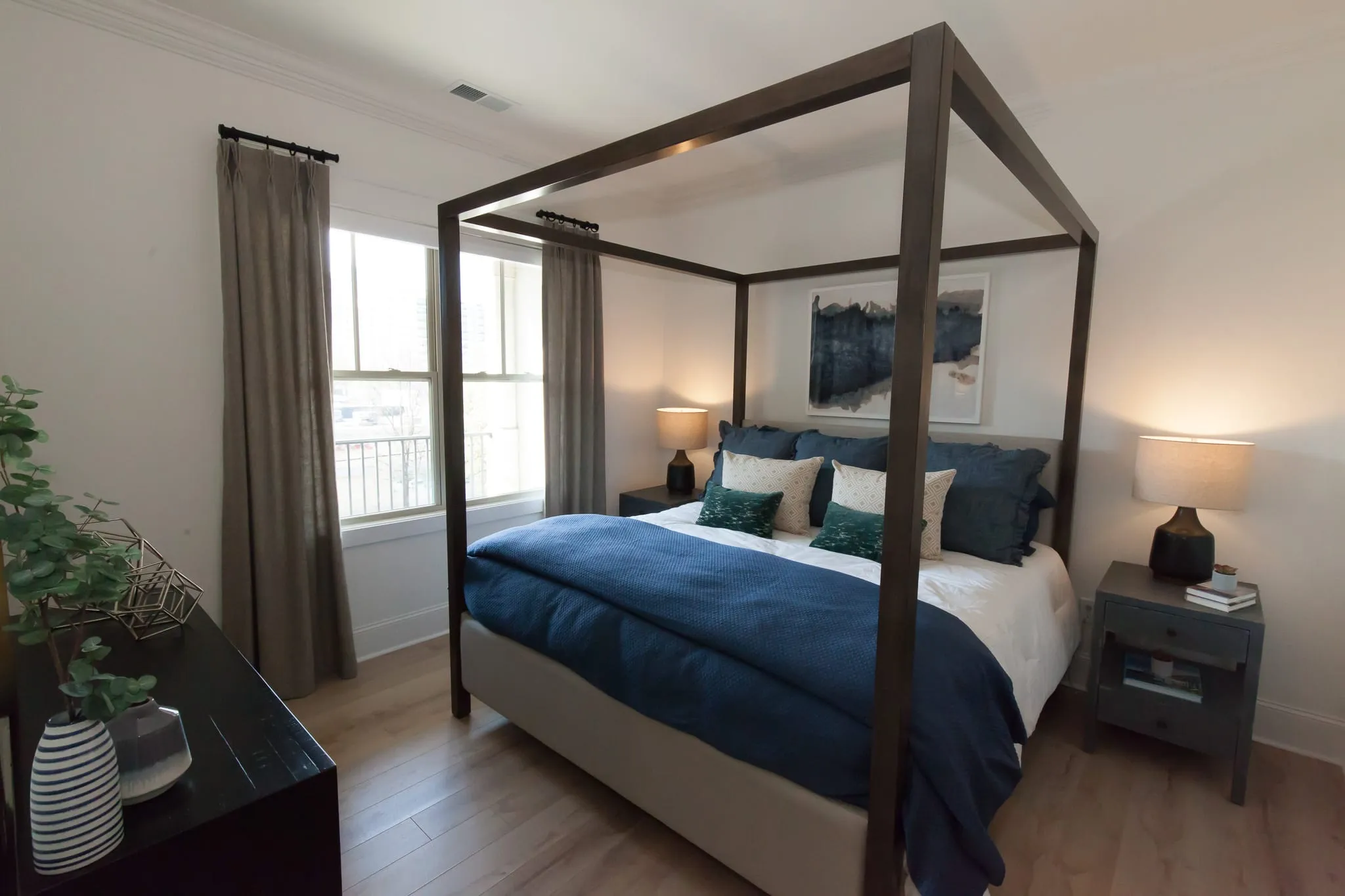 Multifamily apartment bedroom with a dark wood canopy bed and navy bedding