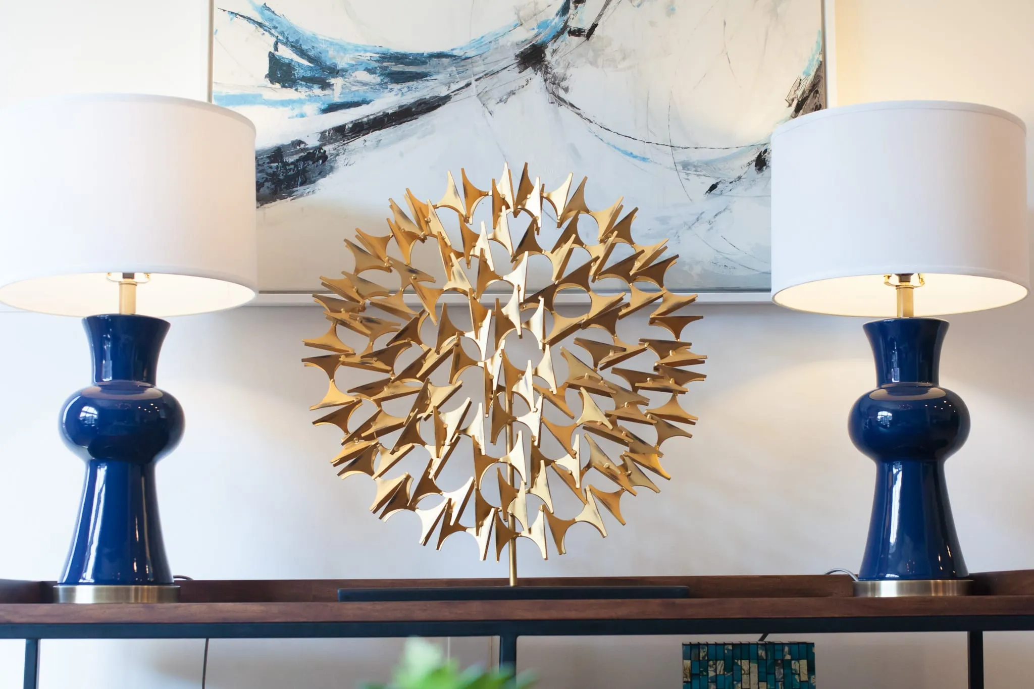Multifamily interior detail: console with navy gourd lamps flanking a gilt starburst sculpture