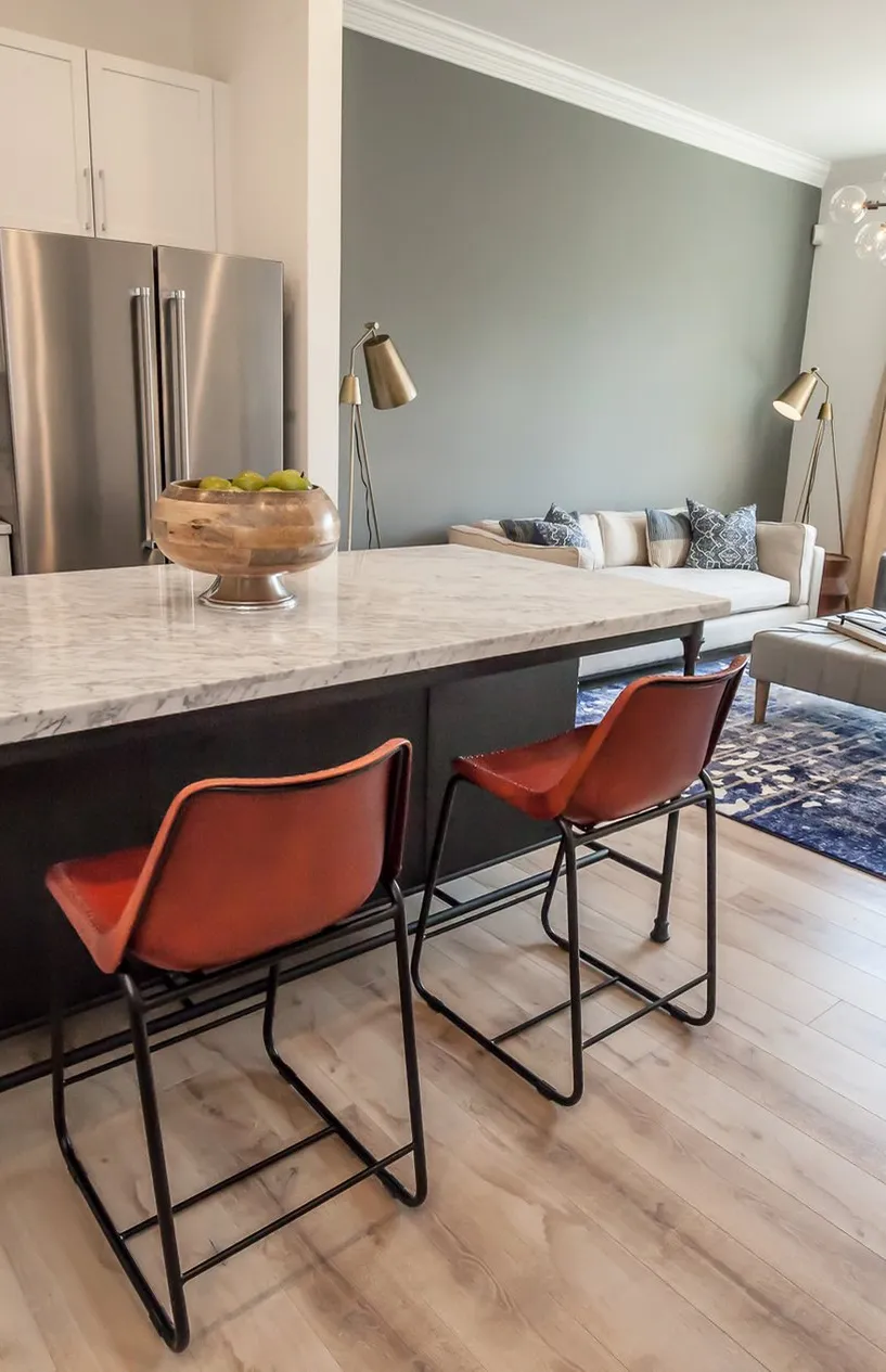 Multifamily model apartment kitchen with a marble island and rust leather stools, interior design by Banko Design at Harper on Piedmont, Atlanta, Georgia