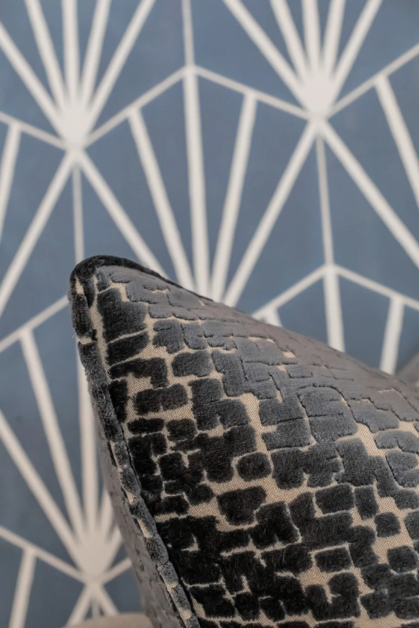 Multifamily amenity interior detail: black and cream cut velvet pillow against blue fan-pattern tile