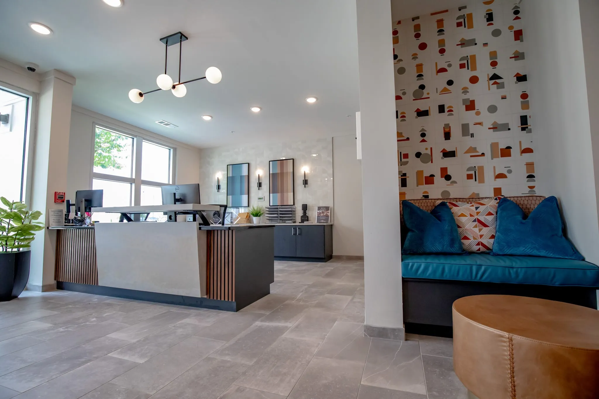 Multifamily amenity leasing area with a leasing desk beside a teal banquette nook lined in geometric shape wallcovering