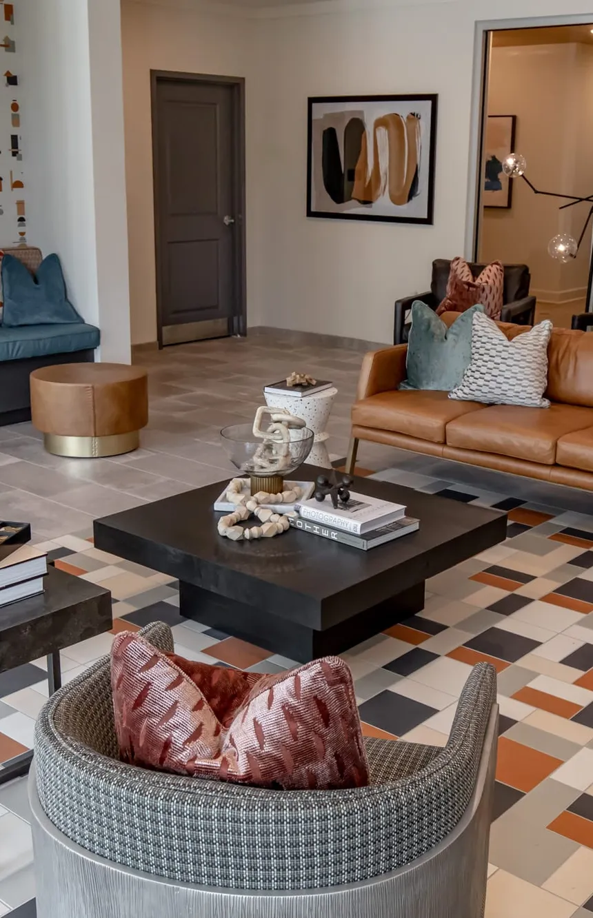 Multifamily amenity lobby lounge with a tan leather sofa on patterned tile, interior design by Banko Design at Hudson Renaissance, Wilmington, North Carolina