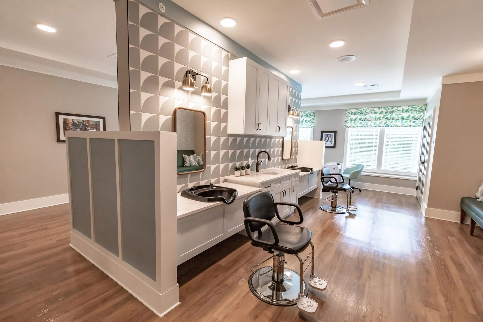 Senior living salon from the entry, shampoo sink and black chairs along sculptural white tile toward a window