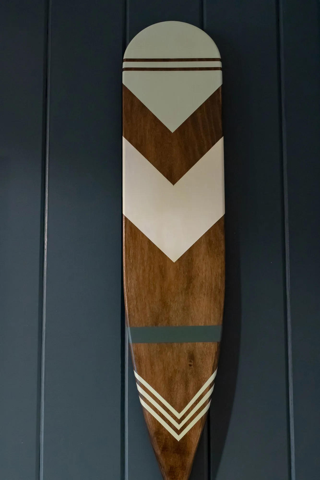 Senior living interior detail: wooden canoe paddle painted with white chevrons mounted on navy paneling