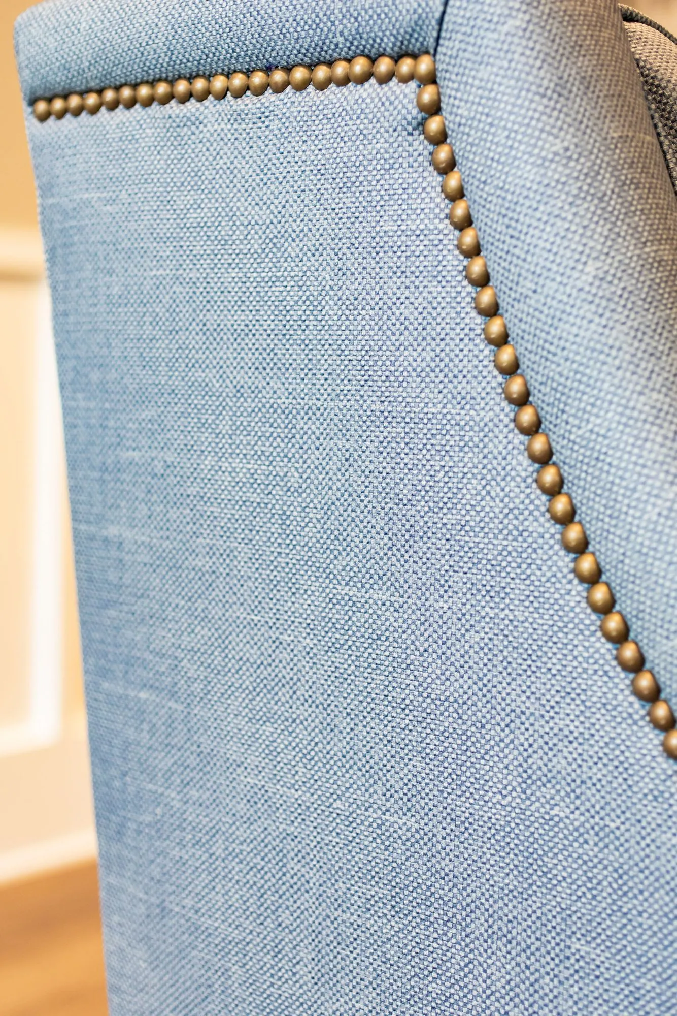 Senior living interior detail: nailhead trim along a pale blue linen upholstered chair