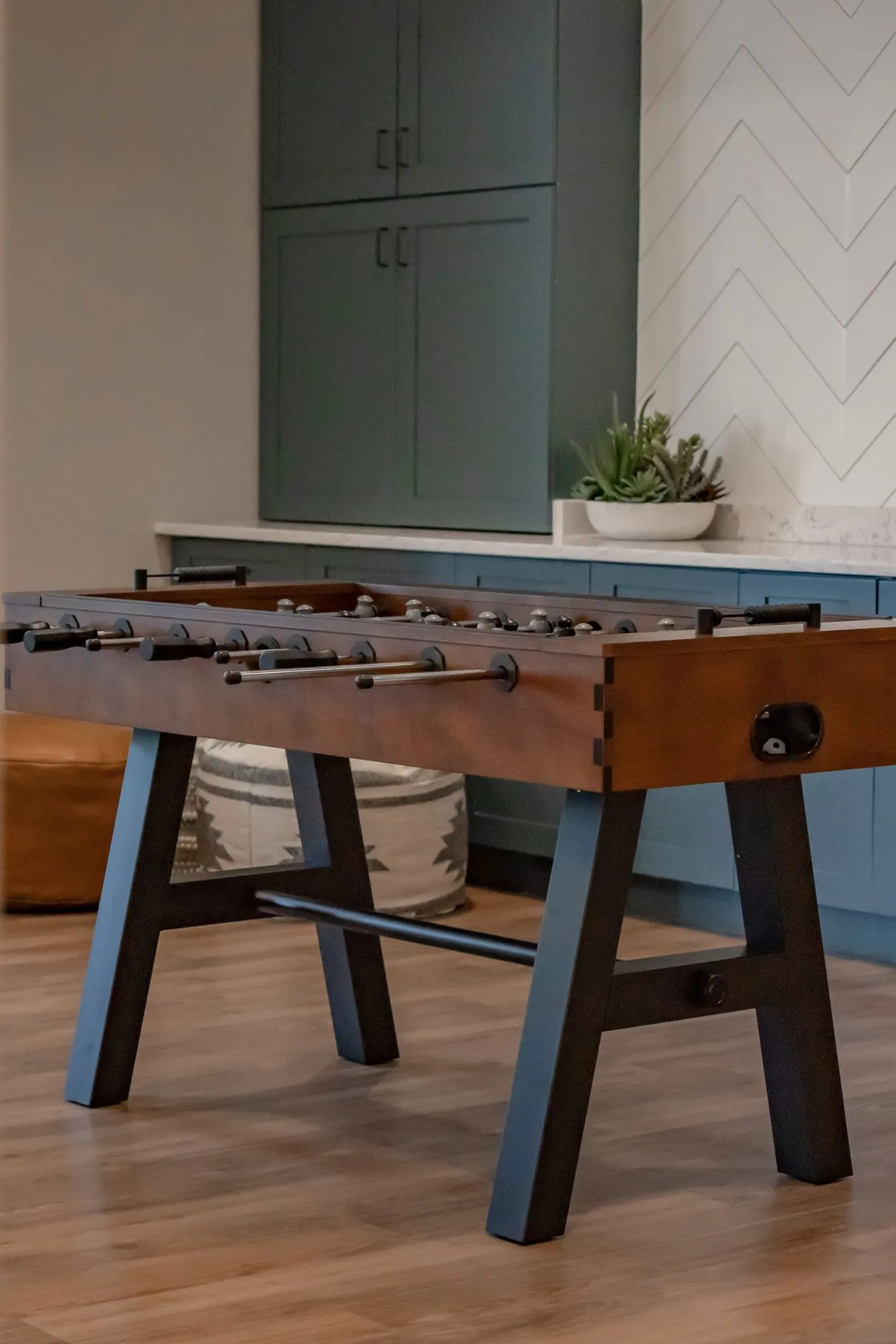 Senior living interior detail: foosball table, a succulent on the counter and a woven pouf behind