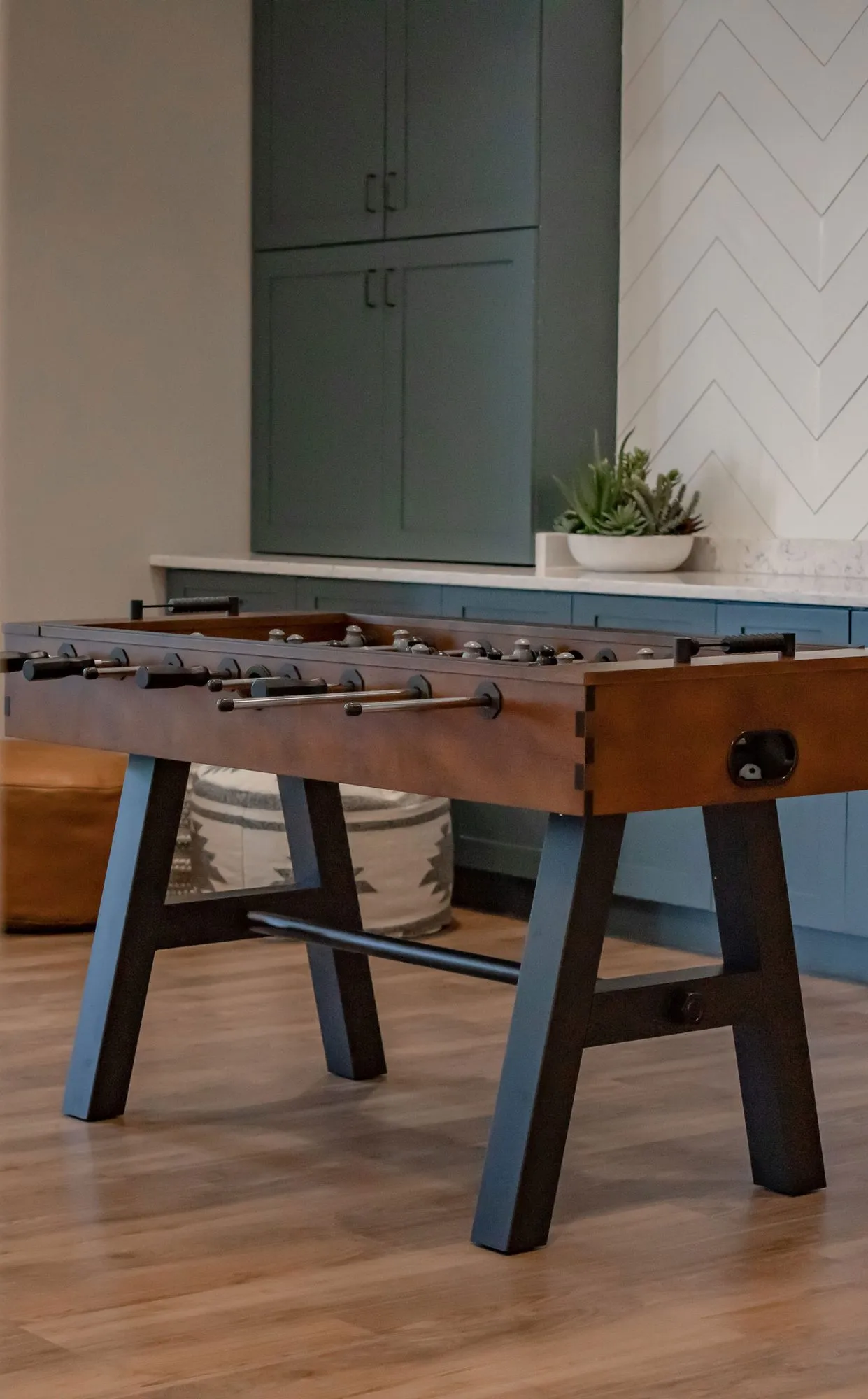 Senior living interior detail: foosball table on the wood floor, tall teal cabinets above