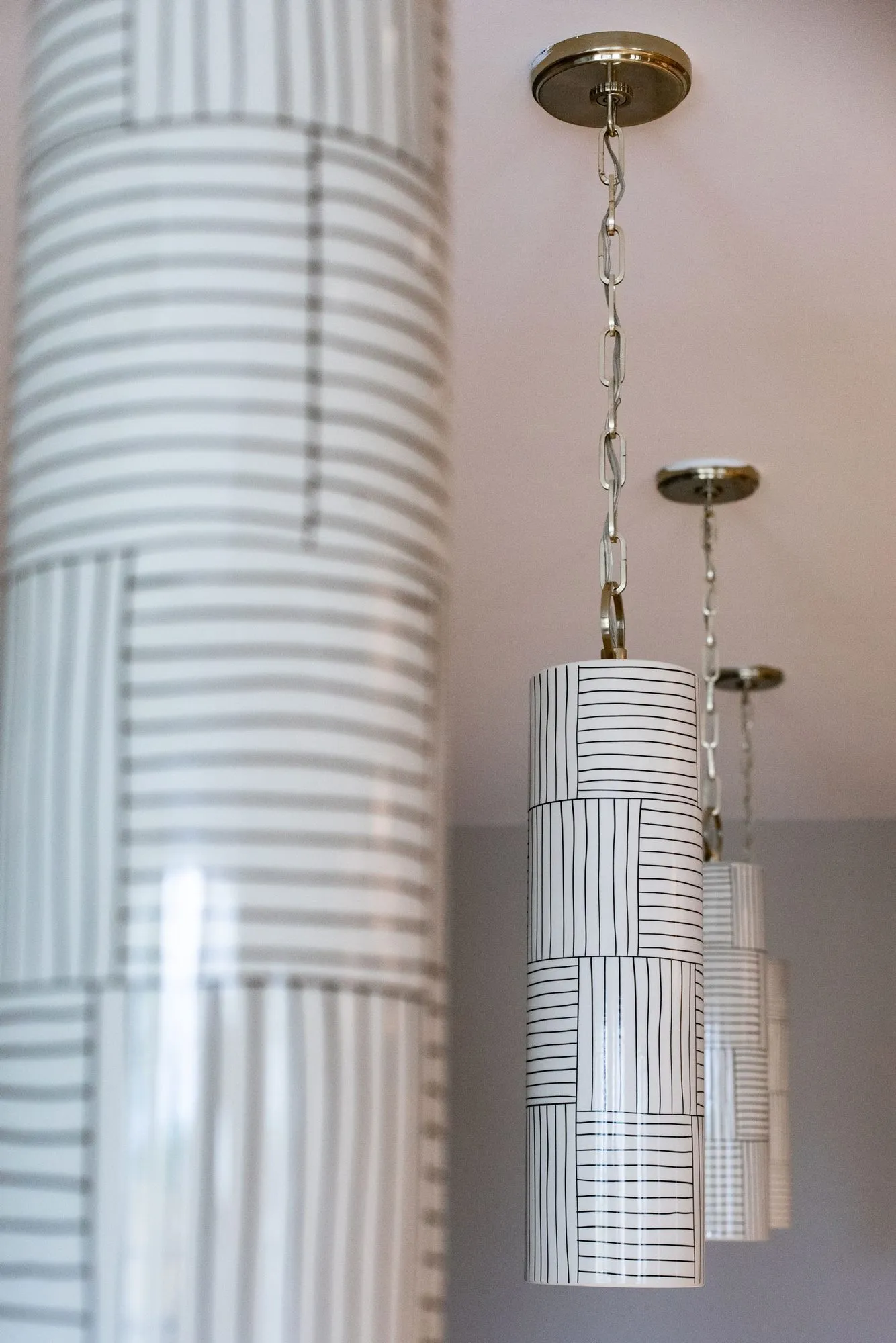 Senior living interior detail: cylindrical pendants with white and grey striped shades on brass rods
