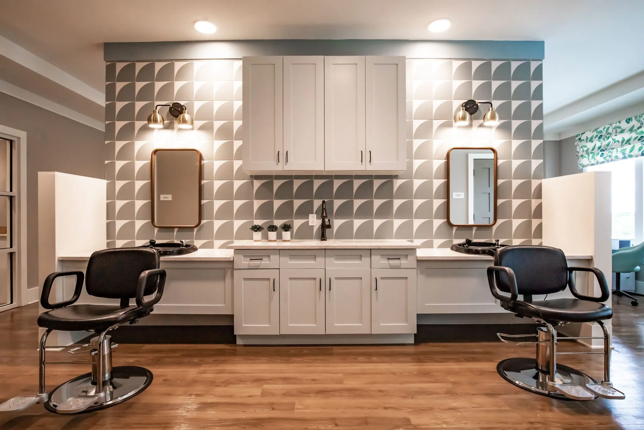 Senior living salon with black styling chairs at brass mirrors against a wall of three-dimensional white tile