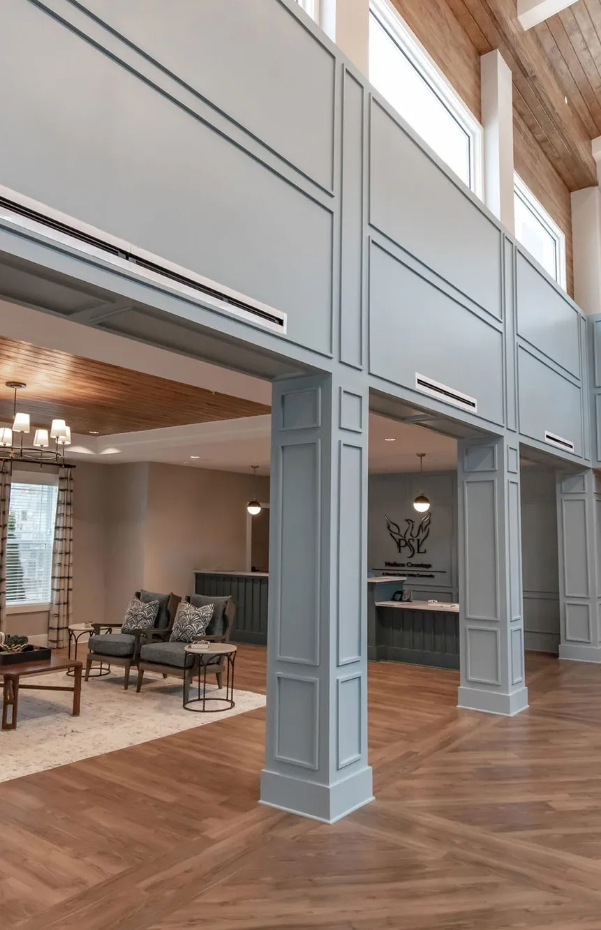 Senior living two storey lobby with pale blue panelling and a wood barrel ceiling, interior design by Banko Design at Madison Crossings, Madison, Alabama