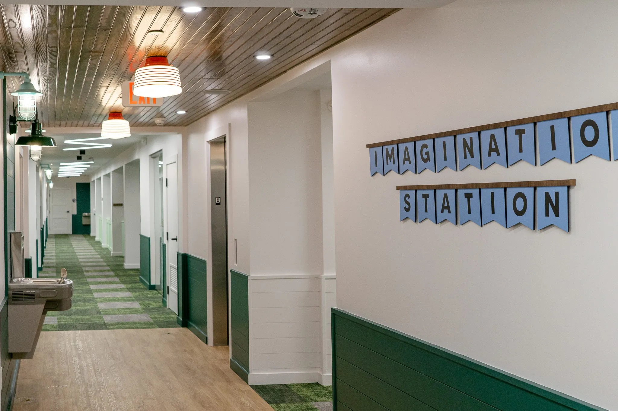 School corridor with Imagination Station spelled across pennants above the green wainscot
