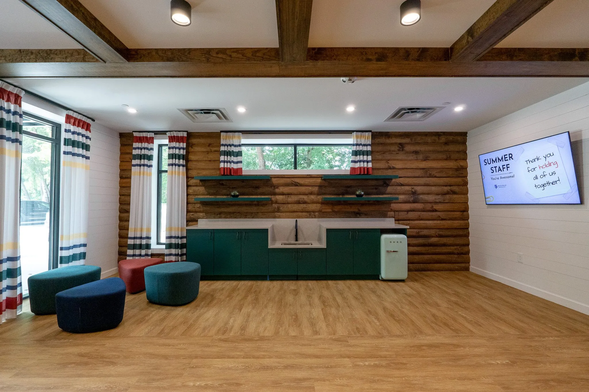 School craft room with a log-sided wall and green cabinetry, a farmhouse sink and a mint refrigerator