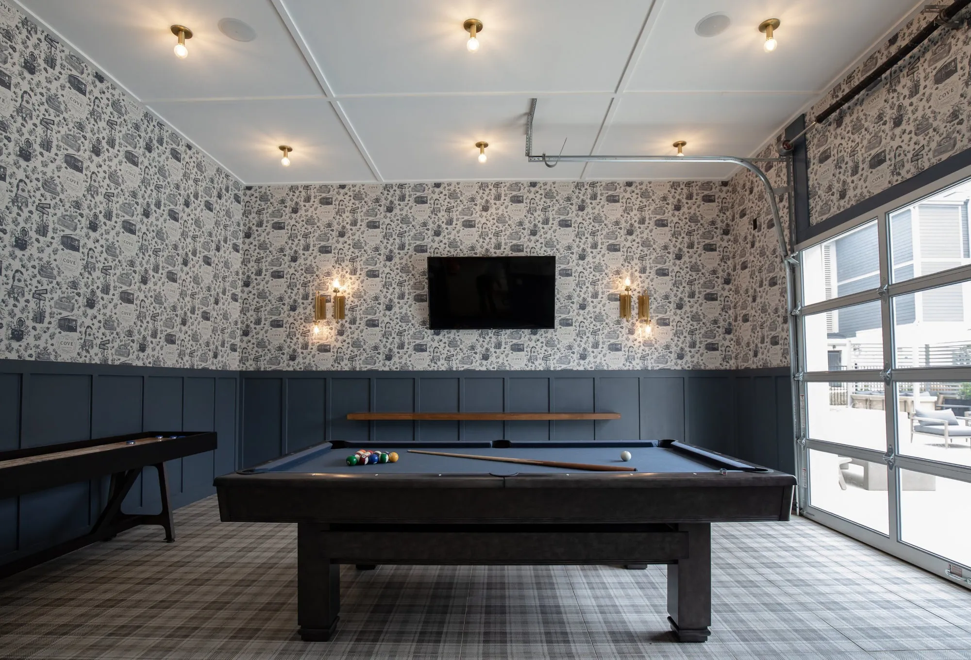 Multifamily amenity game room at Cove at Covington with toile wallpaper, a pool table, shuffleboard and a garage door