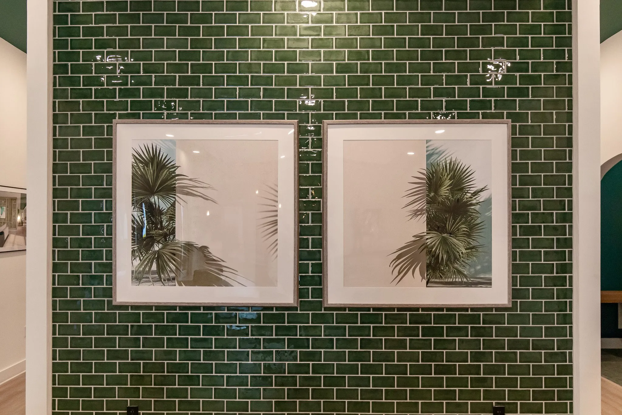 Multifamily interior detail: two framed palm prints on a green subway tile wall