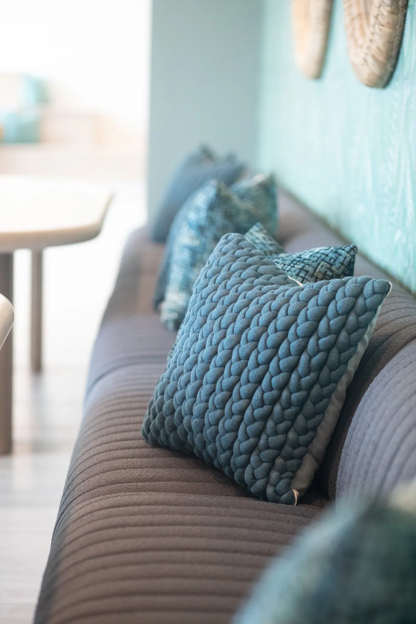 Multifamily interior detail: knitted and teal pillows along a grey channelled banquette