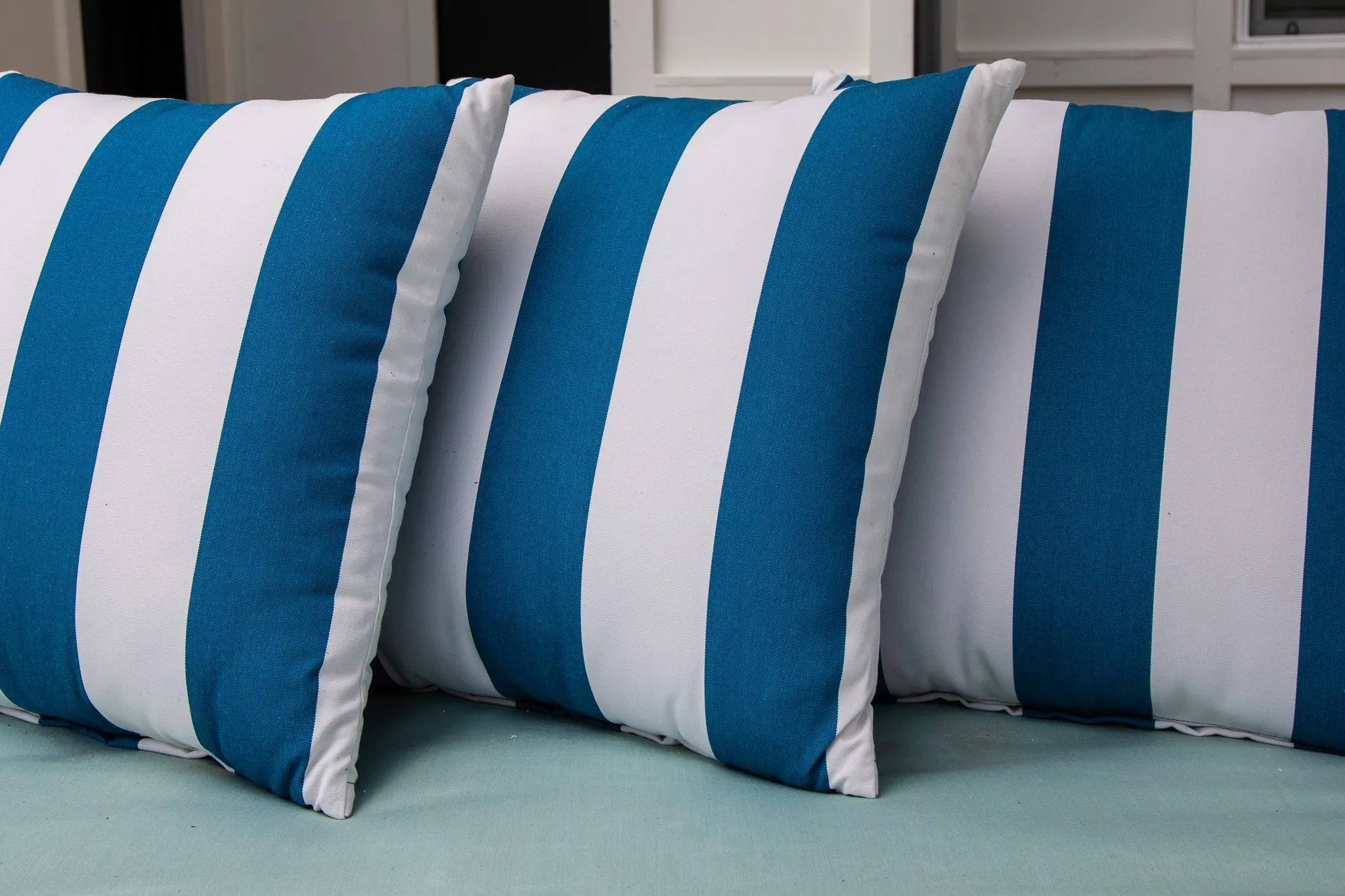 Multifamily outdoor detail: blue and white striped outdoor pillows on a mint cushion