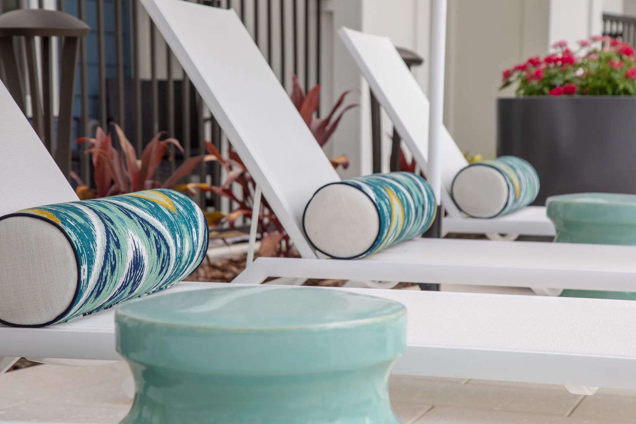 Multifamily outdoor detail: white chaise loungers with blue patterned bolsters and mint ceramic side tables