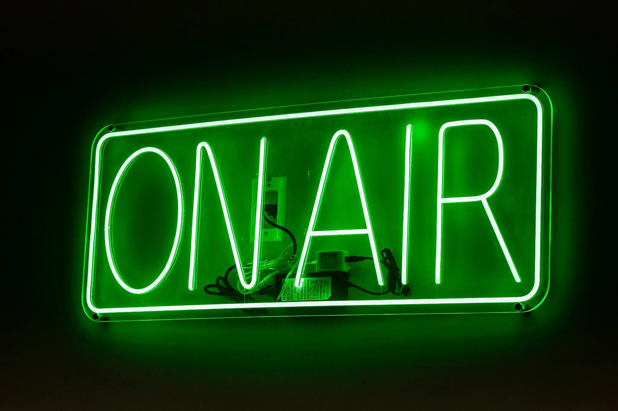 Multifamily interior detail: green neon On Air sign glowing on a dark wall