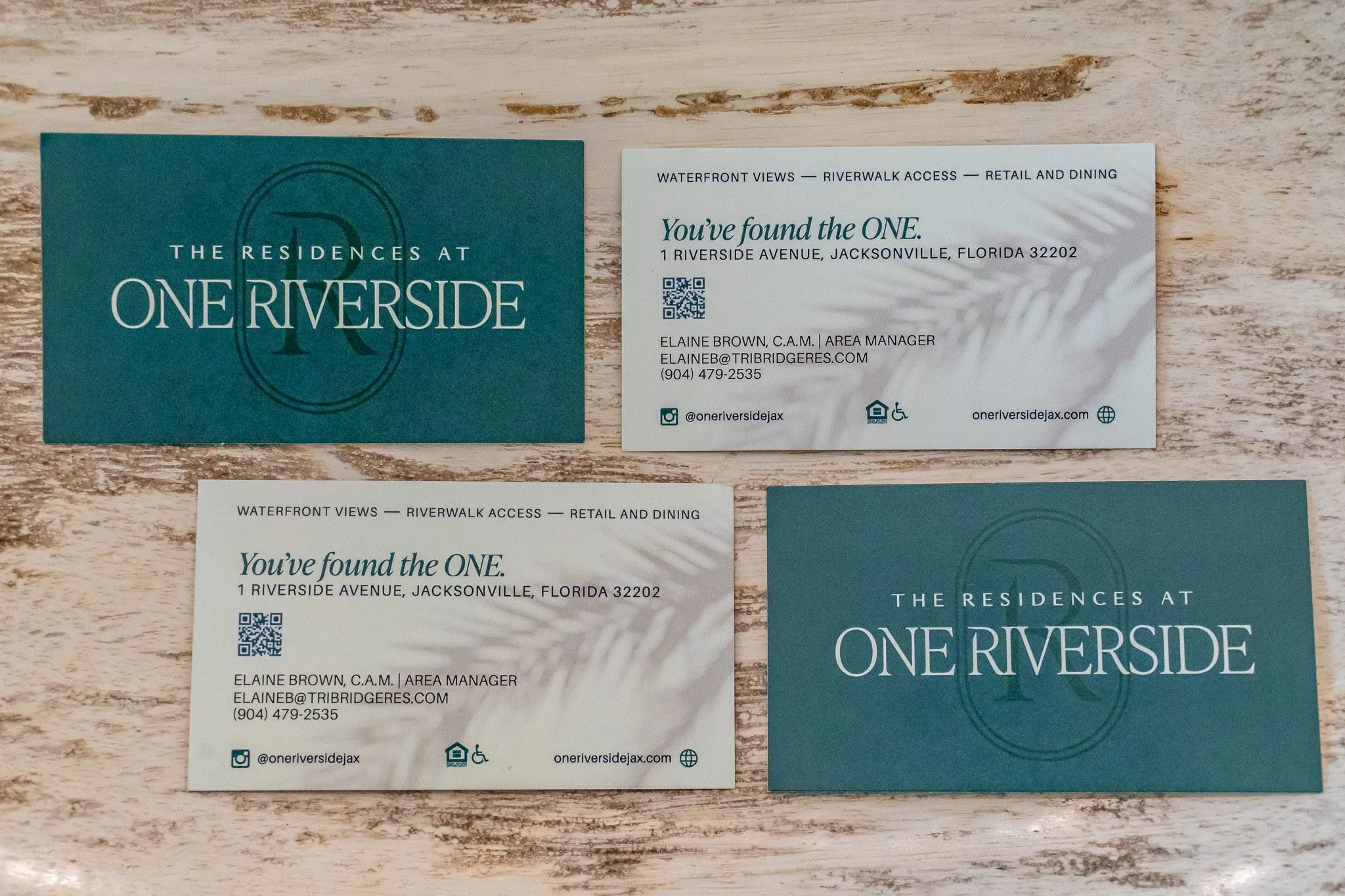 Multifamily leasing collateral: teal and white business cards arranged on a stone surface