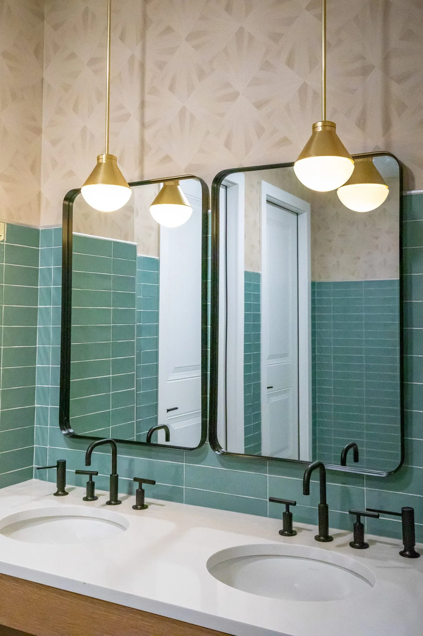 Multifamily amenity restroom vanity with two black framed mirrors, globe pendants, black faucets and green tile