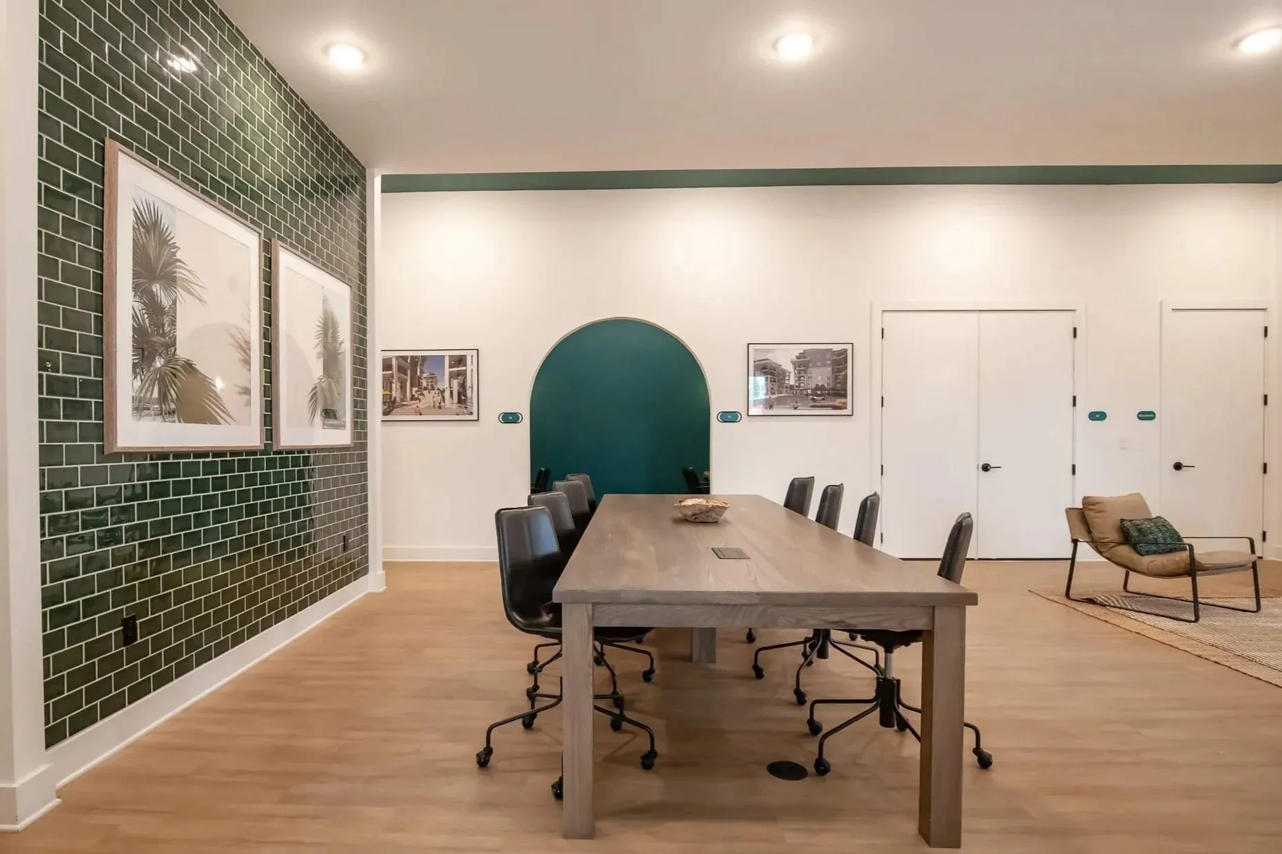 Multifamily amenity conference room with a wood table beside a green tiled wall, interior design by Banko Design at One Riverside, Jacksonville, Florida