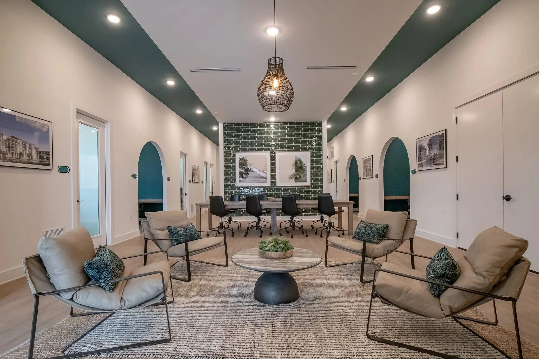 Multifamily amenity lounge with arched teal niches, sling chairs around a round table and a conference table beyond