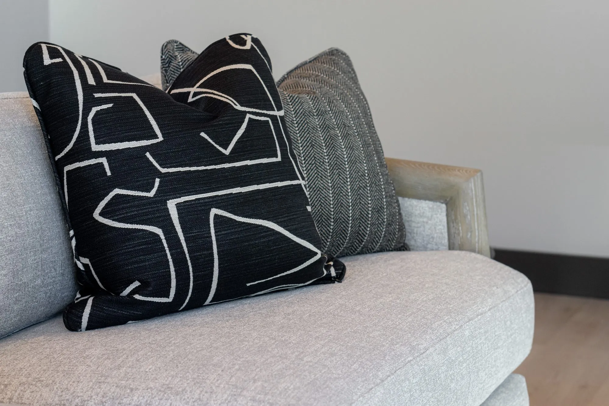 Multifamily interior detail: black and white graphic pillow and a striped pillow on a grey sofa