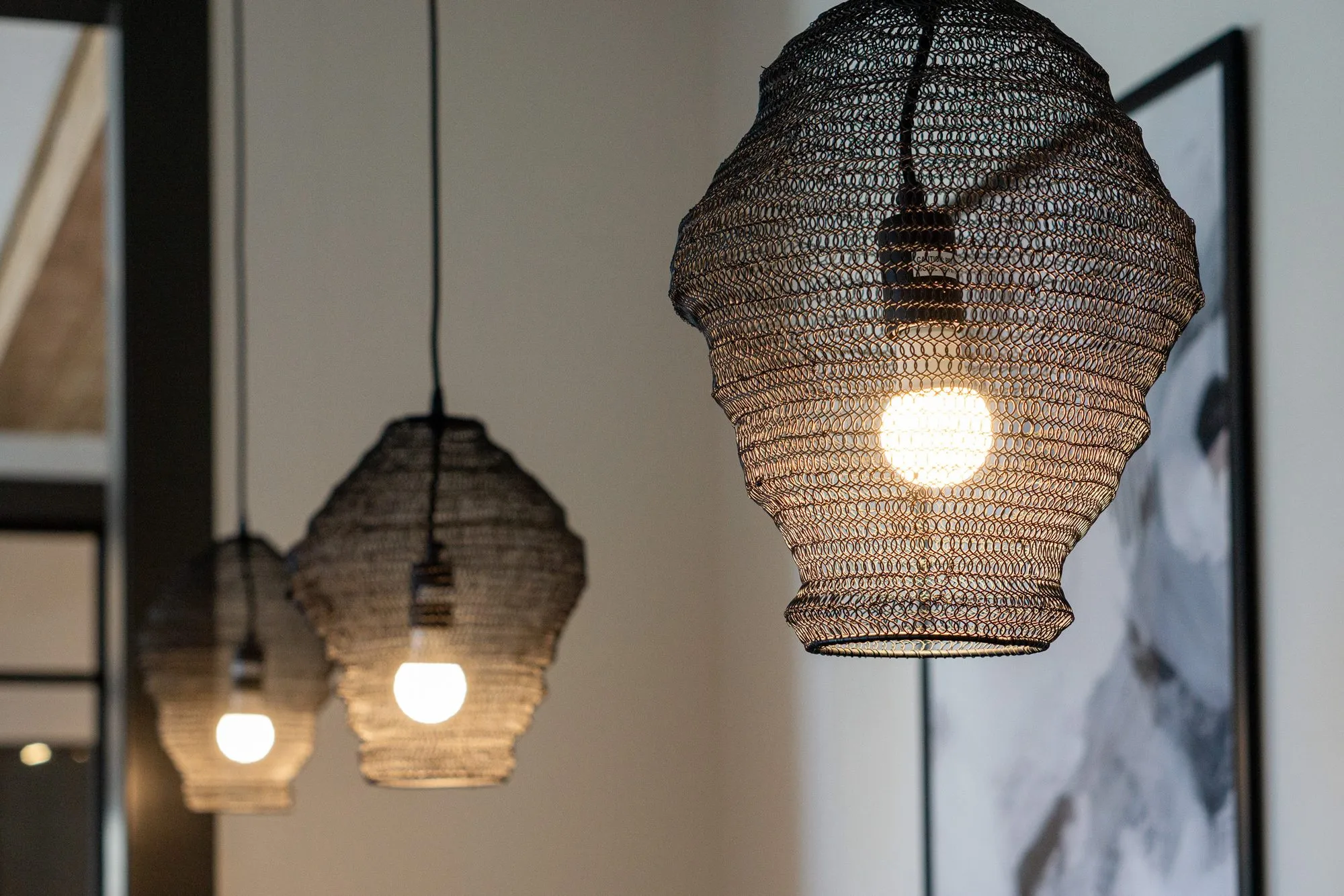 Multifamily interior detail: three black wire mesh pendants with bare bulbs
