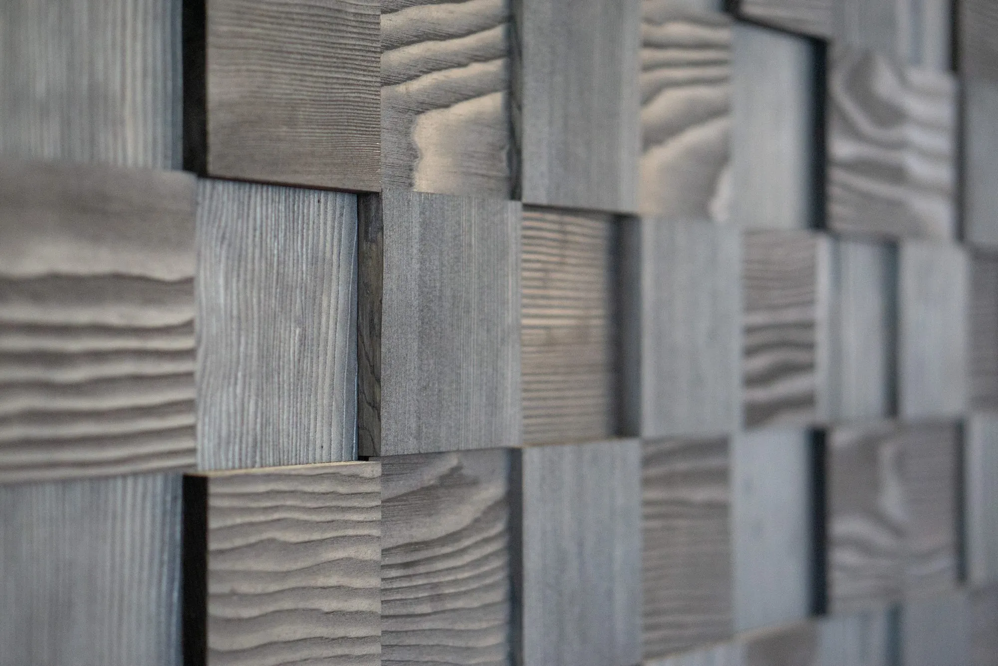 Multifamily interior detail: wall of grey weathered wood blocks set at varying depths