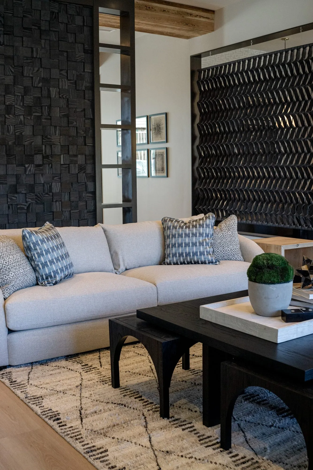 Multifamily amenity lounge with a cream sofa, patterned pillows and a black coffee table between dark textured walls