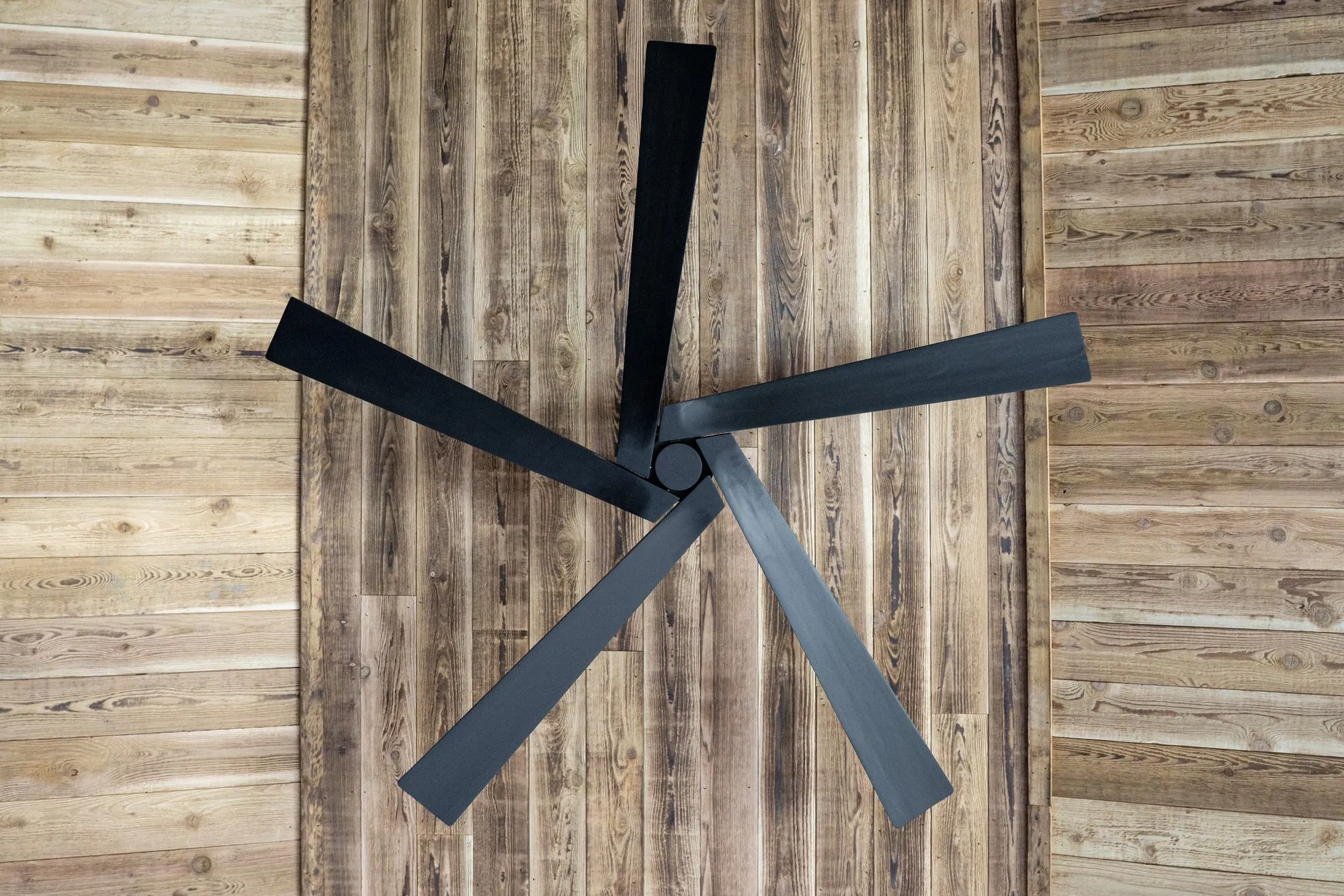 Multifamily interior detail: black five blade ceiling fan against a weathered plank ceiling